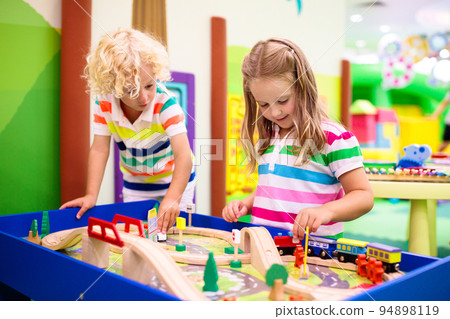 Kids play wooden railroad. Child with toy train. 94898119