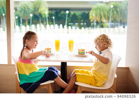 Kids eat cake at restaurant. Boy and girl in cafe. 94898326