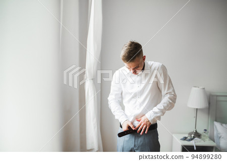 Grooms morning preparation. Handsome man getting dressed and preparing for the wedding 94899280