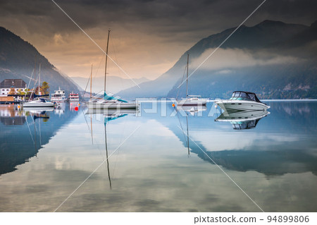 Sailboats in Achensee lake near Innsbruck at peaceful dawn, Tyrol alps, Austria Sailboats in Achensee lake near Innsbruck at peaceful dawn, Tyrol alps, Austria 94899806