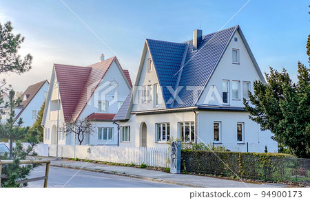 A private house of two floors with triangular roof and an area near the house against a blue sky A private house of two floors with triangular roof and an area near the house against a blue sky 94900173