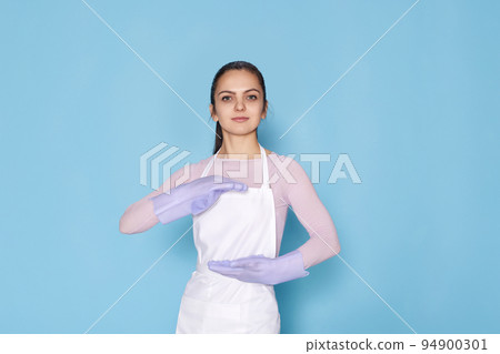 woman in gloves and cleaner apron showing measure symbol gesture 94900301