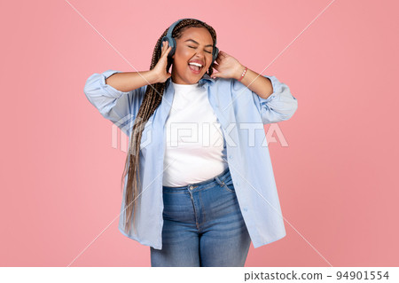 Happy Black Plus Size Woman Singing Wearing Headphones, Pink Background 94901554