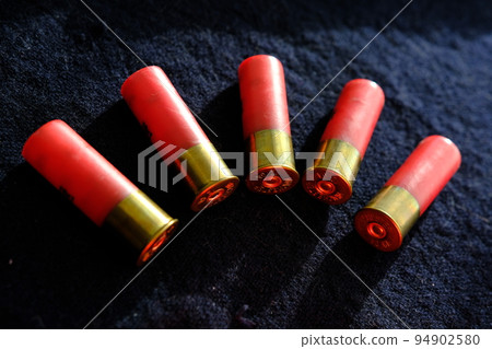 Shotgun shells on a black surface. Ammunition for 12 gauge smoothbore weapons. Hunting ammunition. Dark background. Shotgun shells on a black surface. Ammunition for 12 gauge smoothbore weapons. Hunting ammunition. Dark background. 94902580