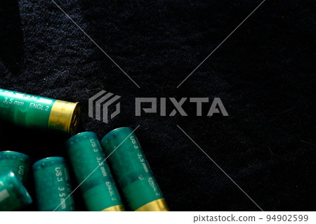 Shotgun shells on a black surface. Ammunition for 12 gauge smoothbore weapons. Hunting ammunition. Dark background. Shotgun shells on a black surface. Ammunition for 12 gauge smoothbore weapons. Hunting ammunition. Dark background. 94902599