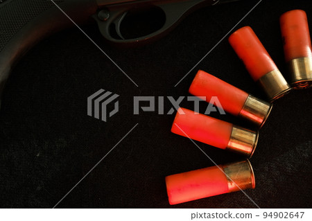 Trigger of a rifle on black background with red lightning with Shotgun shells on a black surface. Ammunition for 12 gauge smoothbore weapons. Hunting ammunition. Dark background. Trigger of a rifle on black background with red lightning with Shotgun shells on a black surface. Ammunition for 12 gauge smoothbore weapons. Hunting ammunition. Dark background. 94902647