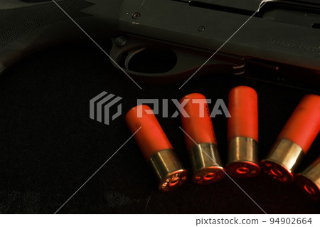 Trigger of a rifle on black background with red lightning with Shotgun shells on a black surface. Ammunition for 12 gauge smoothbore weapons. Hunting ammunition. Dark background. Trigger of a rifle on black background with red lightning with Shotgun shells on a black surface. Ammunition for 12 gauge smoothbore weapons. Hunting ammunition. Dark background. 94902664