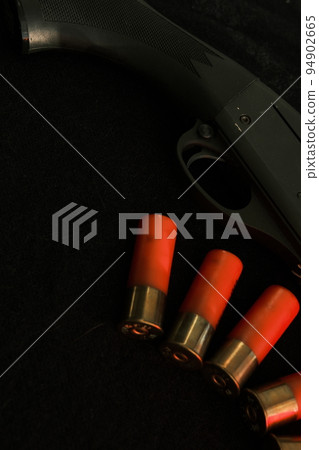 Trigger of a rifle on black background with red lightning with Shotgun shells on a black surface. Ammunition for 12 gauge smoothbore weapons. Hunting ammunition. Dark background. Trigger of a rifle on black background with red lightning with Shotgun shells on a black surface. Ammunition for 12 gauge smoothbore weapons. Hunting ammunition. Dark background. 94902665