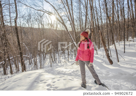 Winter snowshoe hike. Snowshoeing asian multiracial woman in winter forest on hike in snow wearing snowshoes living healthy active outdoor lifestyle. Winter snowshoe hike. Snowshoeing asian multiracial woman in winter forest on hike in snow wearing snowshoes living healthy active outdoor lifestyle. 94902672