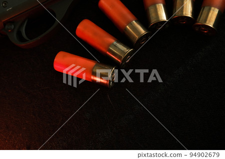 Trigger of a rifle on black background with red lightning with Shotgun shells on a black surface. Ammunition for 12 gauge smoothbore weapons. Hunting ammunition. Dark background. Trigger of a rifle on black background with red lightning with Shotgun shells on a black surface. Ammunition for 12 gauge smoothbore weapons. Hunting ammunition. Dark background. 94902679
