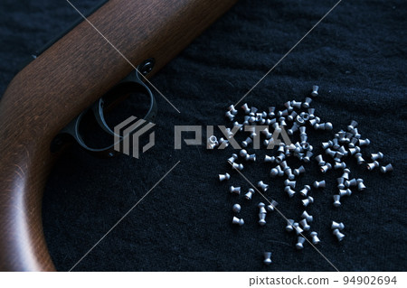 Rifle gun trigger with air pellets for hunting on cloth dark background with red light Rifle gun trigger with air pellets for hunting on cloth dark background with red light 94902694