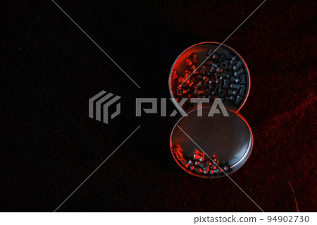 air gun pellets on darck cloth background with red light for illumination air gun pellets on darck cloth background with red light for illumination 94902730