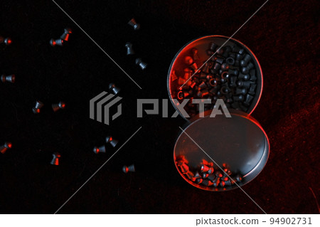 air gun pellets on darck cloth background with red light for illumination 94902731