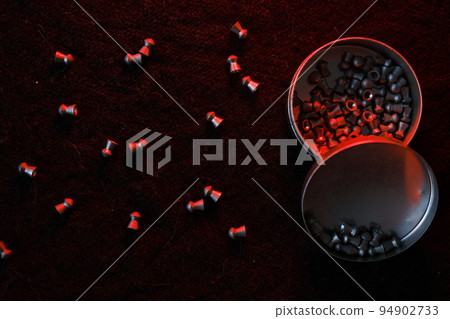 air gun pellets on darck cloth background with red light for illumination 94902733