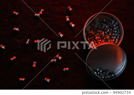 air gun pellets on darck cloth background with red light for illumination air gun pellets on darck cloth background with red light for illumination 94902734