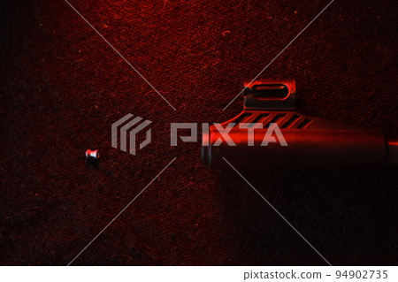 Rifle gun with air pellets for hunting on cloth dark background with red light illumination of the muzzle and pallet 94902735