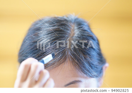 一位中年婦女正在為她不斷增長的白髮上色 94902825