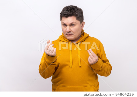 Portrait of handsome middle aged man standing and looking at camera with money or italian gesture with hand, wearing urban style hoodie. Indoor studio shot isolated on white background. Portrait of handsome middle aged man standing and looking at camera with money or italian gesture with hand, wearing urban style hoodie. Indoor studio shot isolated on white background. 94904239