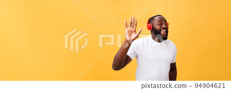 Young African American man wearing headphone and enjoy music over yellow gold Background Young African American man wearing headphone and enjoy music over yellow gold Background 94904621
