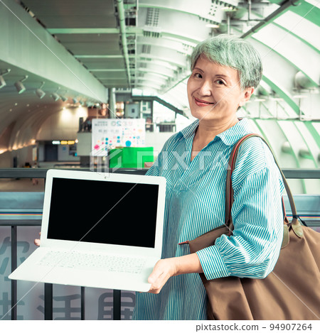 A 60-year-old Asian elderly woman smiles in public when she displays a blank screen, writes a video screen, and uses a blank screen to create an advertisement. A 60-year-old Asian elderly woman smiles in public when she displays a blank screen, writes a video screen, and uses a blank screen to create an advertisement. 94907264