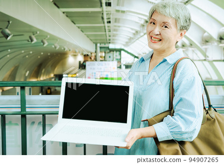 A 60-year-old Asian elderly woman smiles in public when she displays a blank screen, writes a video screen, and uses a blank screen to create an advertisement. A 60-year-old Asian elderly woman smiles in public when she displays a blank screen, writes a video screen, and uses a blank screen to create an advertisement. 94907265