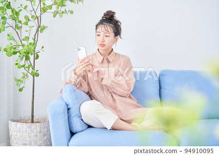 年輕女子在房間裡使用智能手機 年輕女子在房間裡使用智能手機 94910095