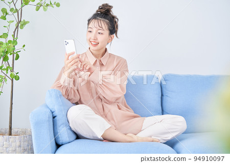 年輕女子在房間裡使用智能手機 年輕女子在房間裡使用智能手機 94910097
