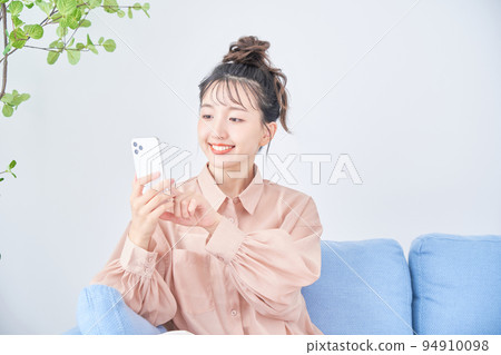 年輕女子在房間裡使用智能手機 年輕女子在房間裡使用智能手機 94910098