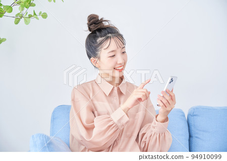 Young woman using smart phone in the room Young woman using smart phone in the room 94910099