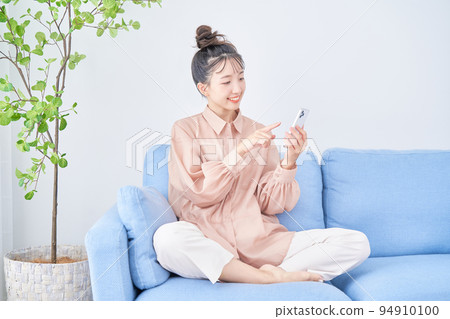 Young woman using smart phone in the room 94910100