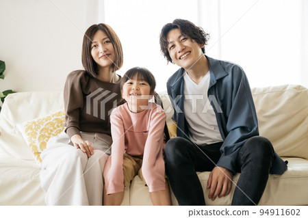 Smiling family sitting on the sofa/child-rearing image 94911602
