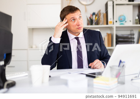 Pensive businessman working with papers Pensive businessman working with papers 94911691