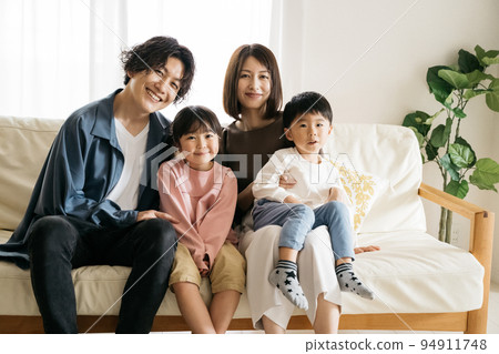 Smiling family sitting on the sofa/child-rearing image 94911748