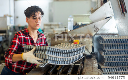 Woman carrying cell seed trays in agricultural facility 94911775