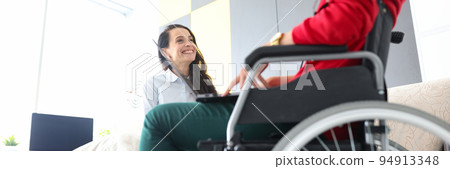 Woman in wheelchair communicates with friend at home closeup 94913348