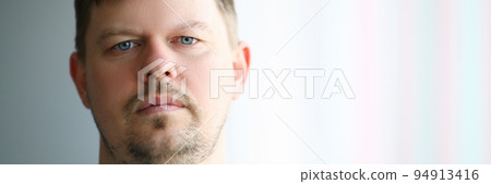 Portrait of young sad man in front of window Portrait of young sad man in front of window 94913416