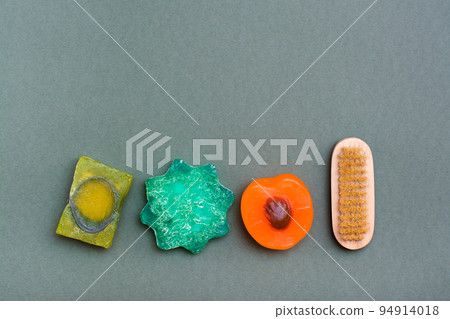 Body care. Different types of handmade soap without additives and a brush on a green background. Body care. Different types of handmade soap without additives and a brush on a green background. 94914018