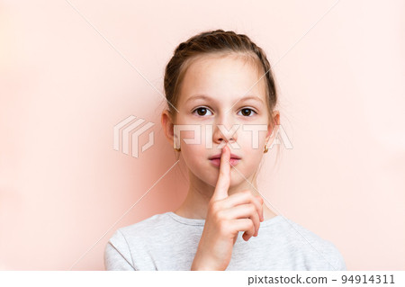 Surprised girl holds her finger in front of her lips. Call for silence Surprised girl holds her finger in front of her lips. Call for silence 94914311