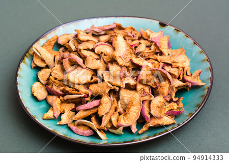 Pieces of dry apples on a plate on a green background. Healthy eating 94914333