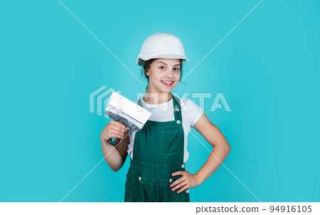 working in repair shop. concept of building and renovation. happy girl use spatula tool. teen builder in safety helmet. young worker in protective hard hat. confident kid use spatula while repairing working in repair shop. concept of building and renovation. happy girl use spatula tool. teen builder in safety helmet. young worker in protective hard hat. confident kid use spatula while repairing 94916105