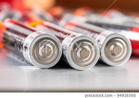 Macro of AA alkaline batteries lying on metal table with blurred energetic background 94916308