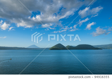 The surface of Lake Toya reflecting the blue sky and flowing clouds The surface of Lake Toya reflecting the blue sky and flowing clouds 94916355