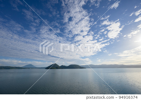 洞爺湖的湖面倒映著藍天、飄逸的白雲和朝陽 洞爺湖的湖面倒映著藍天、飄逸的白雲和朝陽 94916374
