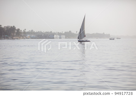 Luxor, Egypt - January 17, 2019: Beautiful fishing and pleasure boats on the Nile in Luxor. Beautiful river and reflections of boats in the water. Clear, sunny day. Luxor, Egypt - January 17, 2019: Beautiful fishing and pleasure boats on the Nile in Luxor. Beautiful river and reflections of boats in the water. Clear, sunny day. 94917728