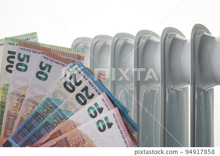 Euro money banknotes on heating radiator battery. Concept of expensive heating costs and rising energy bill Euro money banknotes on heating radiator battery. Concept of expensive heating costs and rising energy bill 94917858