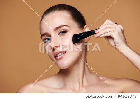 woman applying blush on cheeks with make-up brush woman applying blush on cheeks with make-up brush 94918378