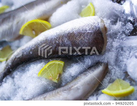 Fresh raw sea fish and lemon peces on ice surface. 94920205