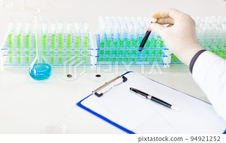 Laboratory. Doctor in protective gloves puts a test tube with an infected blood sample. Laboratory. Doctor in protective gloves puts a test tube with an infected blood sample. 94921252