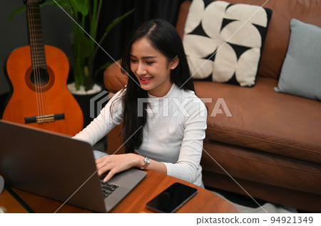 Charming Asian female freelancer or college student working on her tasks on laptop at home. 94921349