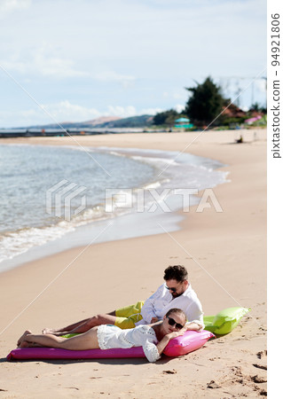 Young couple sunbathing together on the beach near the sea 94921806